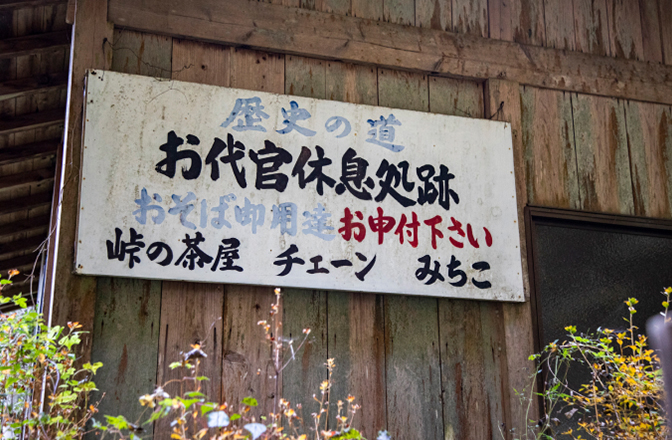 手書きの看板「歴史の道、お代官休息処跡、おそば御用達お申し付け下さい、峠の茶屋 チェーン みちこ」