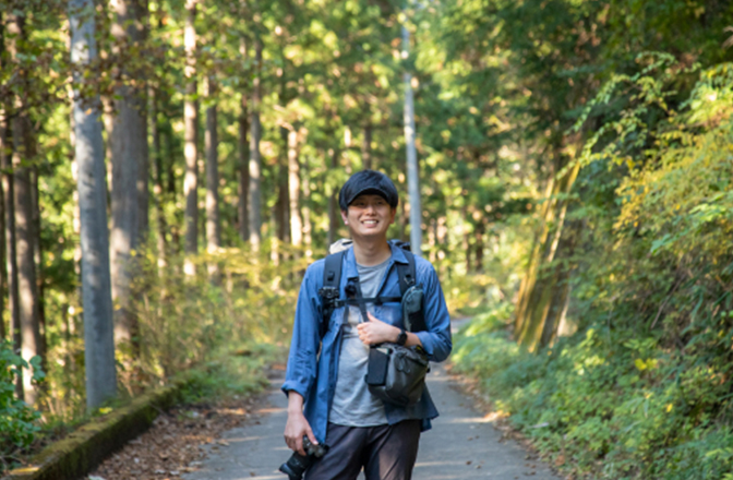 登山を終え、舗装された道に立つJINさん