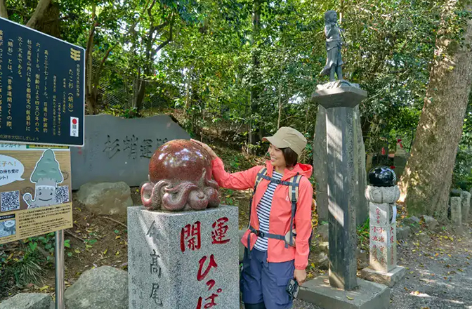 赤いタコの石像を撫でるかほさん