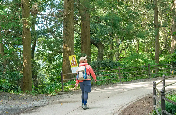 周りの景色を見渡しながら歩道を歩くかほさん