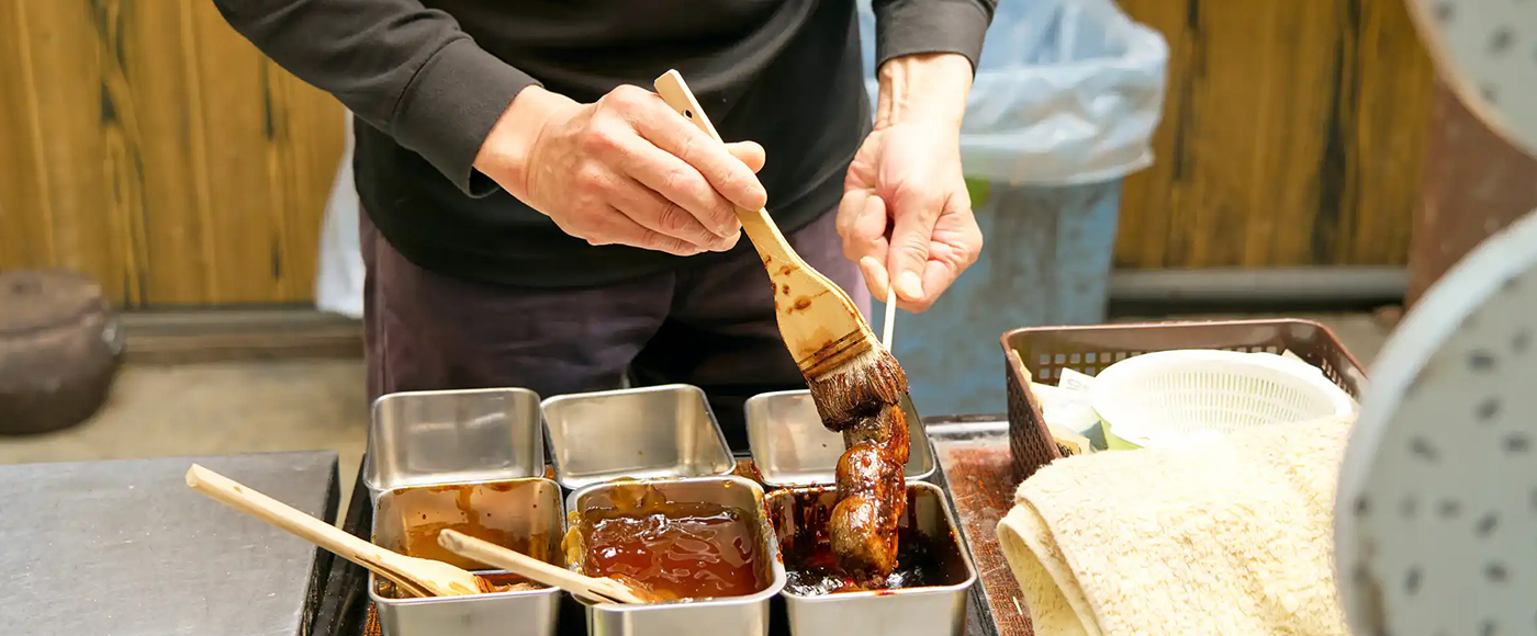 こなれた手つきでお団子にゴマだれを塗る店員さん