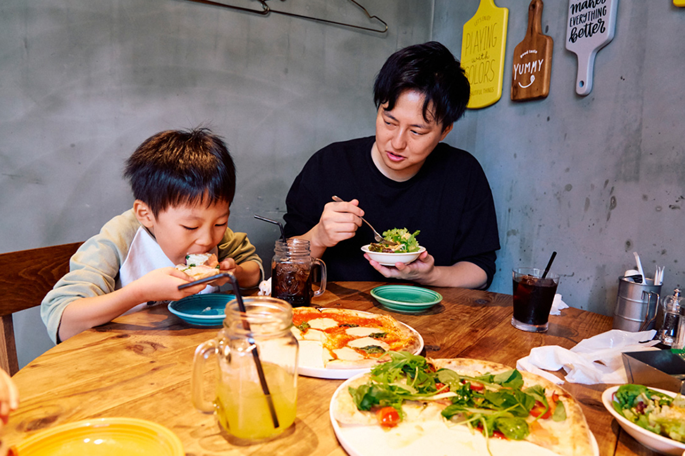 ピザを頬張るいおりくん、サラダを食べるパパ