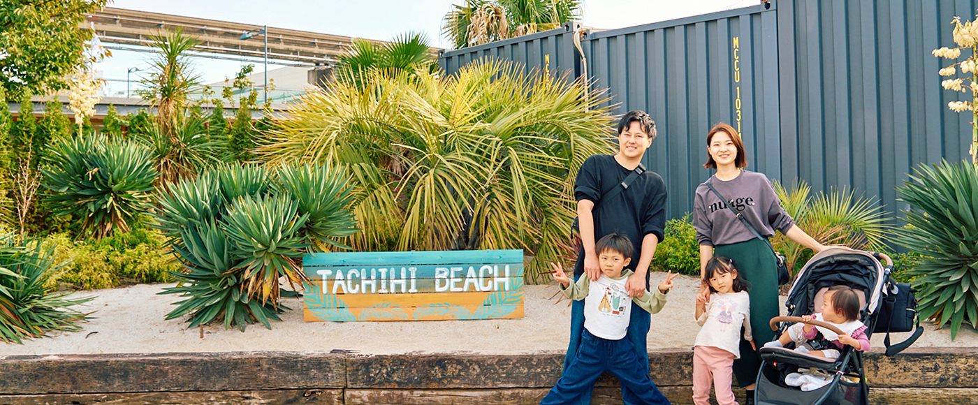 タチヒビーチの看板前でおりおりん一家の家族写真